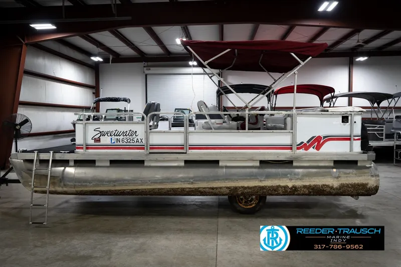 Slide: The Image of 1993 Godfrey Sweetwater pontoon boat in indoor storage, featuring red canopy and side ladder. - 10