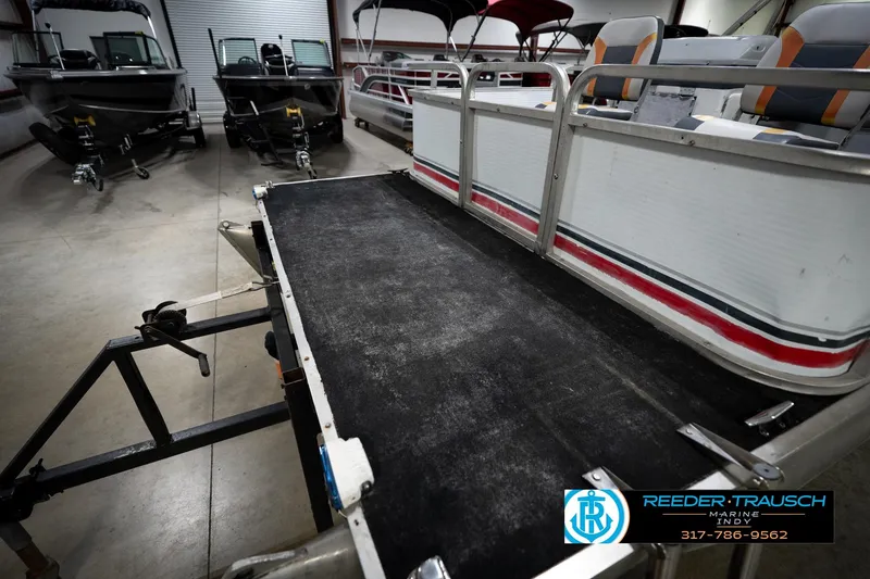 Slide: The Image of 1993 Godfrey Sweetwater pontoon boat in showroom, featuring spacious deck and seating. - 49