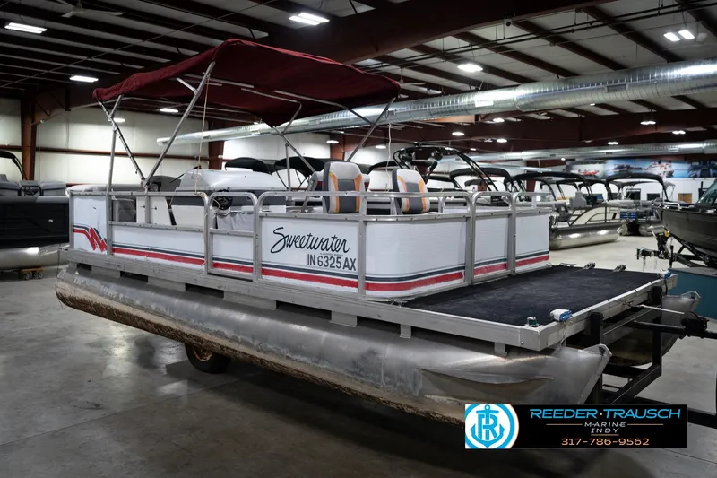 Slide: The Image of 1993 Godfrey Sweetwater pontoon boat with red canopy in indoor showroom. - 5