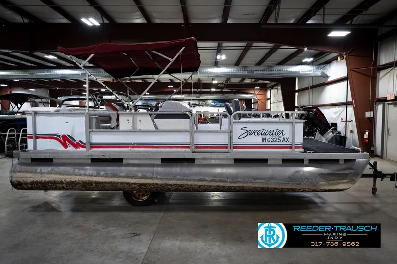 Slide: The Image of 1993 Godfrey Sweetwater pontoon boat in indoor storage, featuring red accents and canopy. - 6