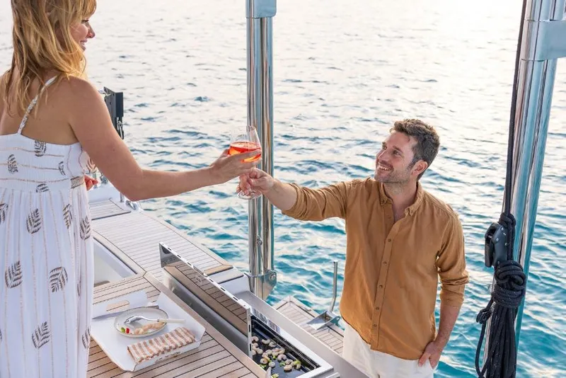 Slide: The Image of Couple enjoying drinks on a 2026 Dufour 48 yacht deck by the sea. - 28