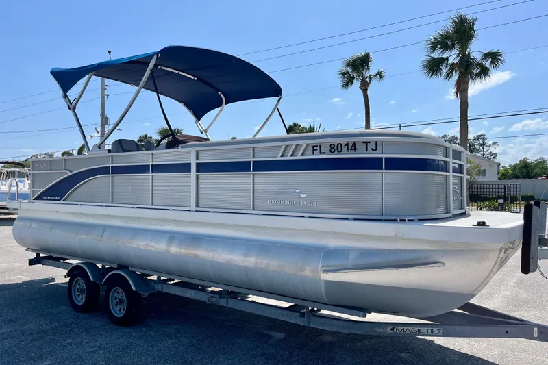 Slide: The Image of 2023 Bennington SX23 pontoon boat on trailer, blue canopy, parked outdoors. - 0