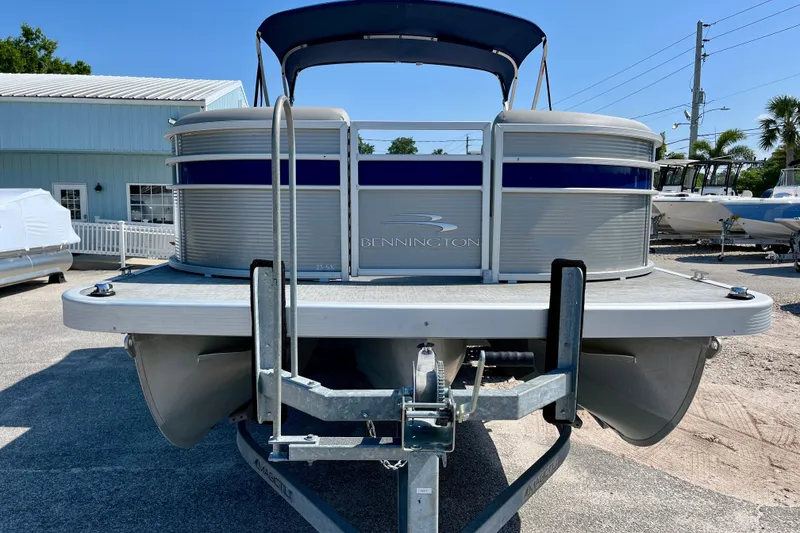 Slide: The Image of 2023 Bennington SX23 pontoon boat on trailer, displayed outdoors. - 1