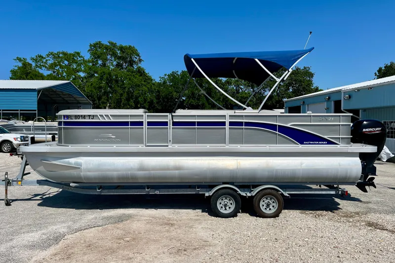 Slide: The Image of 2023 Bennington SX23 pontoon boat with blue canopy on a trailer. - 3