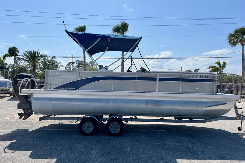 Slide: The Image of 2023 Bennington SX23 pontoon boat with canopy on trailer, parked outdoors. - 7