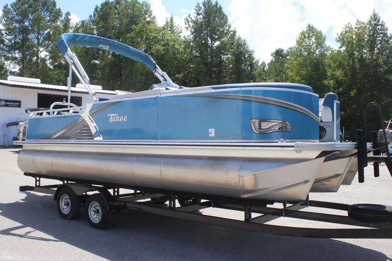 Slide: The Image of 2021 Tahoe Pontoon LTZ Versatile Rear Bench 24' on trailer, blue exterior, parked outdoors. - 3