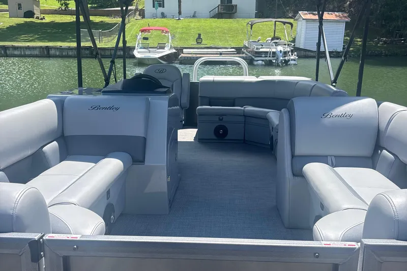 Slide: The Image of 2025 Bentley Pontoons Legacy Cruise XL interior with luxurious seating on a calm lake. - 10