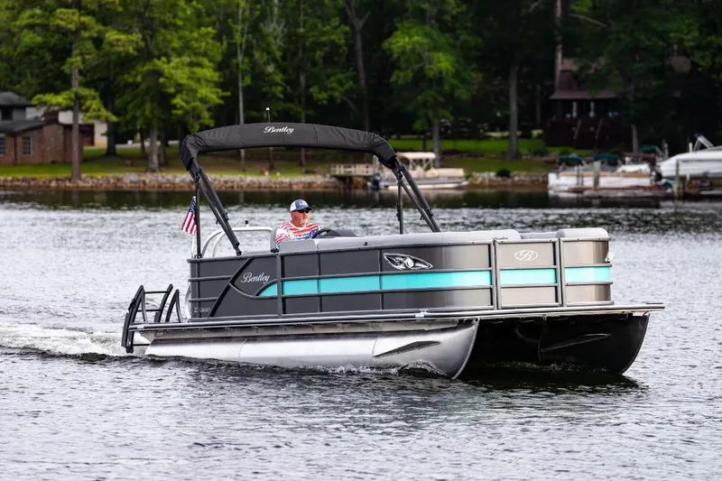 Slide: The Image of 2025 Bentley Pontoons Legacy Cruise XL on a serene lake, showcasing sleek design and performance. - 5