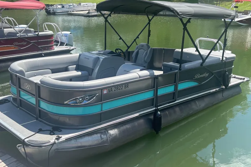 Slide: The Image of 2025 Bentley Pontoons Legacy Cruise XL on calm water, featuring sleek design and spacious seating. - 7