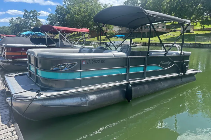 Slide: The Image of 2025 Bentley Pontoons Legacy Cruise XL on a sunny lake, featuring sleek design and canopy. - 8