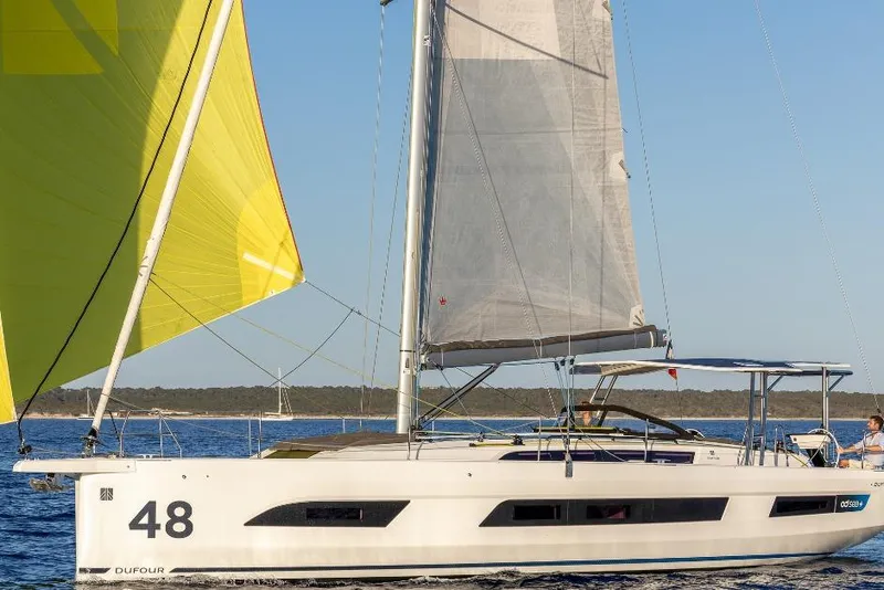 Slide: The Image of 2026 Dufour 48 sailboat with yellow sail cruising on calm waters. - 19