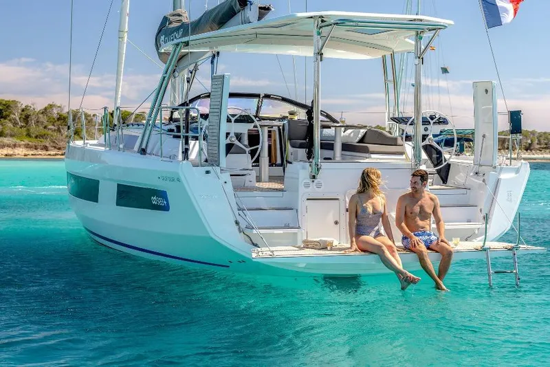 Slide: The Image of Couple relaxing on a 2026 Dufour 48 yacht, enjoying sunny weather and clear waters. - 25