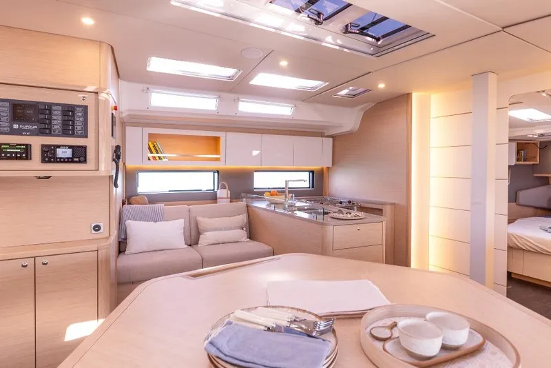 Slide: The Image of 2026 Dufour 48 yacht anchored in a scenic cove with people relaxing onboard. - 28