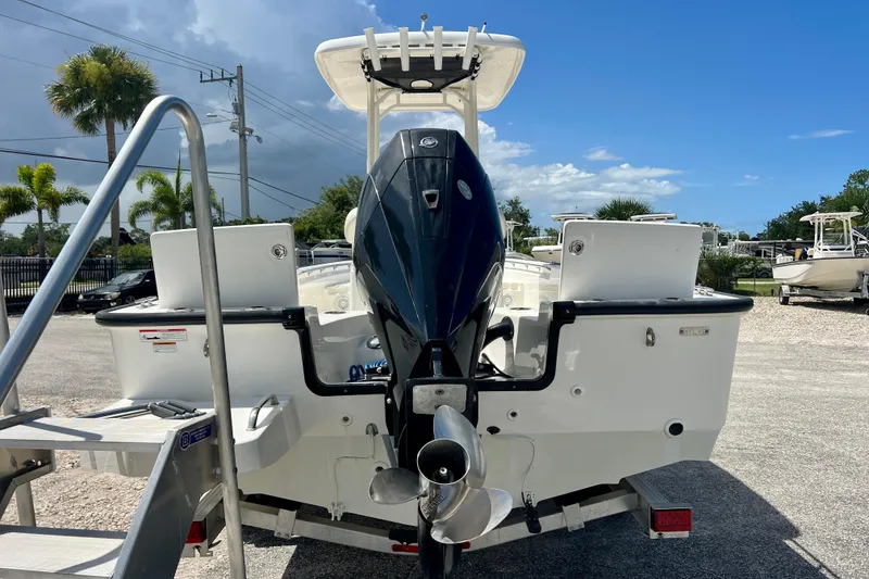 Slide: The Image of 2023 Boston Whaler 210 Montauk boat with outboard motor, parked outdoors under clear blue sky. - 6