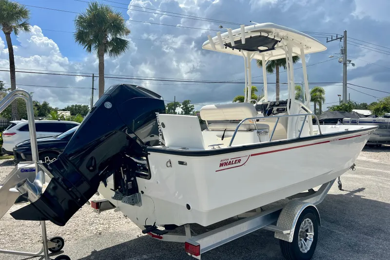 Slide: The Image of 2023 Boston Whaler 210 Montauk boat on trailer, parked outdoors under cloudy sky. - 7