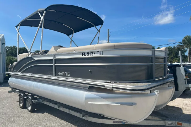The Image of 2023 Harris Cruiser 230 pontoon boat on trailer under blue sky. - 2