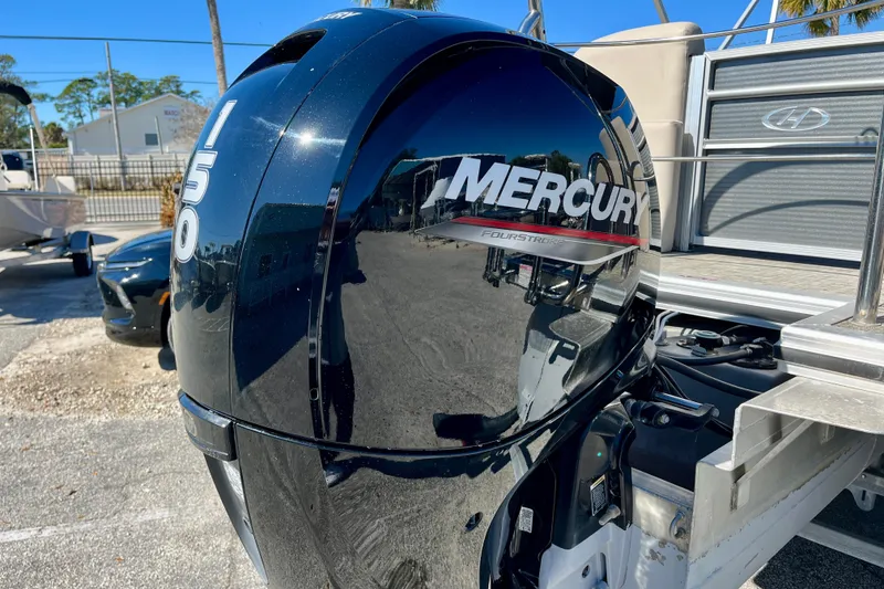 Slide: The Image of 2023 Harris Cruiser 230 with Mercury 150 FourStroke outboard engine, parked outdoors. - 27