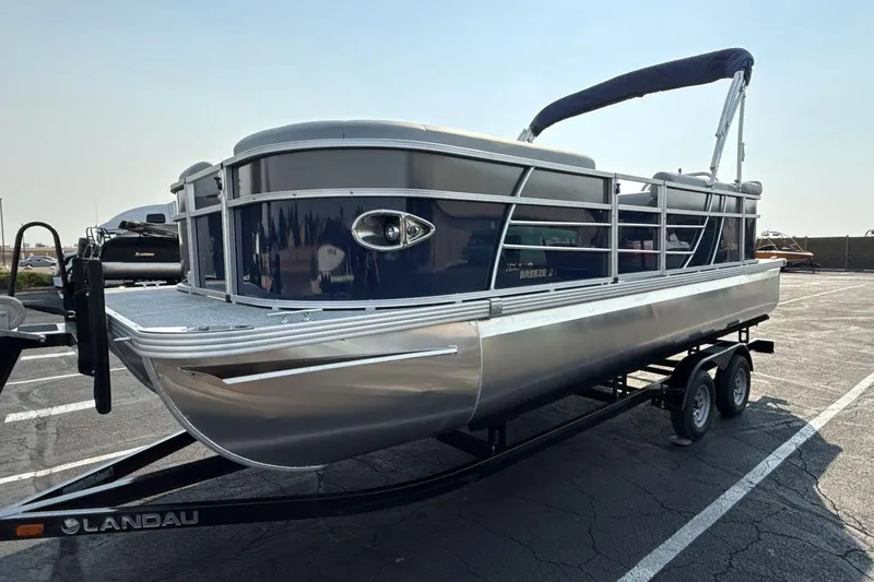 Slide: The Image of 2026 Landau Island Breeze 21 C pontoon boat on trailer in parking lot. - 1