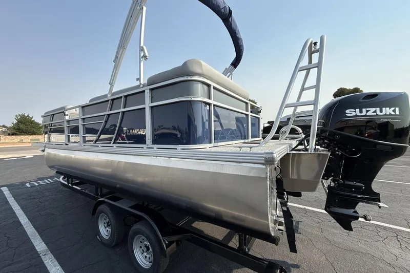 Slide: The Image of 2026 Landau Island Breeze 21 C pontoon boat with Suzuki outboard motor on trailer. - 3