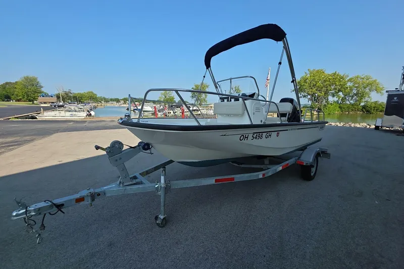 Slide: The Image of 2022 Boston Whaler 150 Montauk boat on trailer near a marina. - 1
