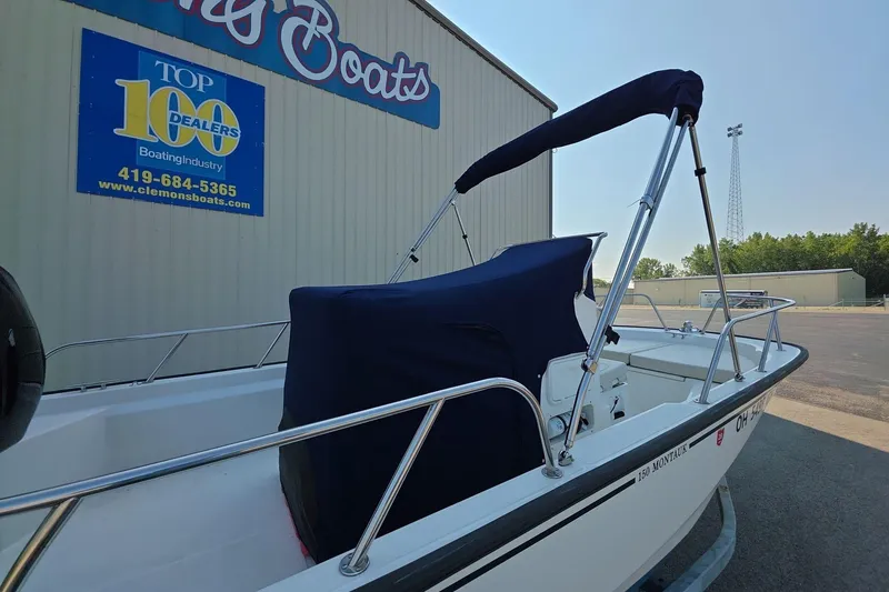 Slide: The Image of 2022 Boston Whaler 150 Montauk boat with cover, parked at Clemons Boats dealership. - 10