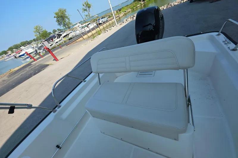 Slide: The Image of 2022 Boston Whaler 150 Montauk boat interior with white seating, dockside view. - 11