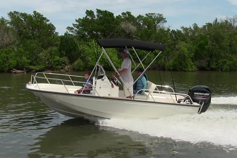 Slide: The Image of 2022 Boston Whaler 150 Montauk boat cruising on a river with passengers. - 14