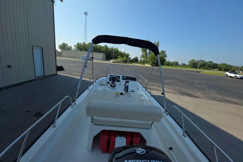 Slide: The Image of 2022 Boston Whaler 150 Montauk boat with canopy, parked outdoors on a sunny day. - 5
