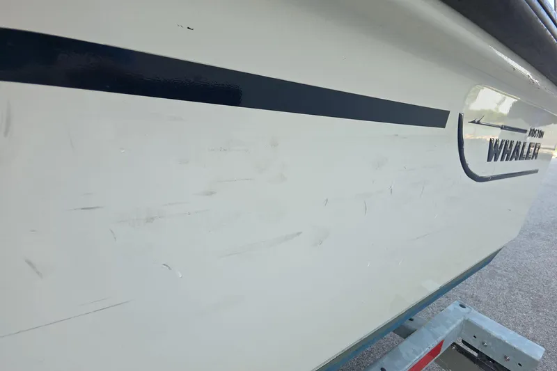 Slide: The Image of 2022 Boston Whaler 150 Montauk boat side view with logo and stripe detail. - 9