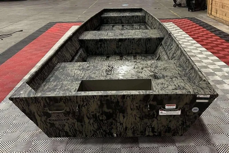 Slide: The Image of 2026 Tracker Grizzly® 15 Jon boat with camouflage design in a showroom setting. - 3
