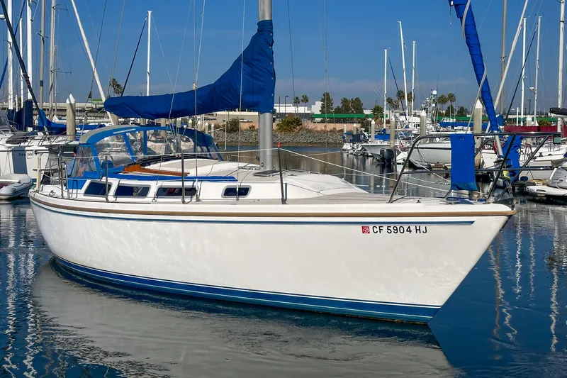 Slide: The Image of 1984 Catalina 30 sailboat docked in a marina, featuring blue sail covers. - 12