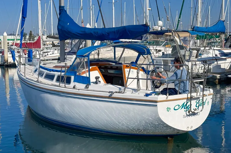 Slide: The Image of 1984 Catalina 30 sailboat docked in marina, featuring blue sail covers and a spacious cockpit. - 13