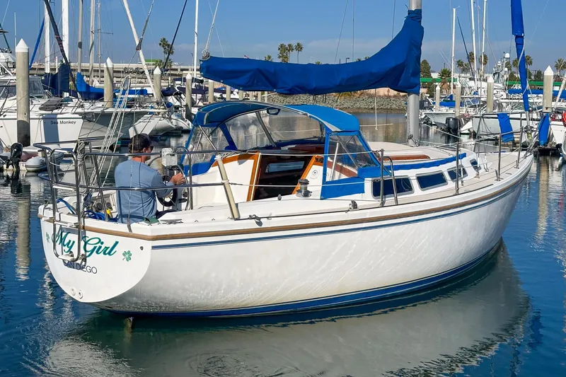 Slide: The Image of 1984 Catalina 30 sailboat docked in marina, featuring blue accents and a person onboard. - 14
