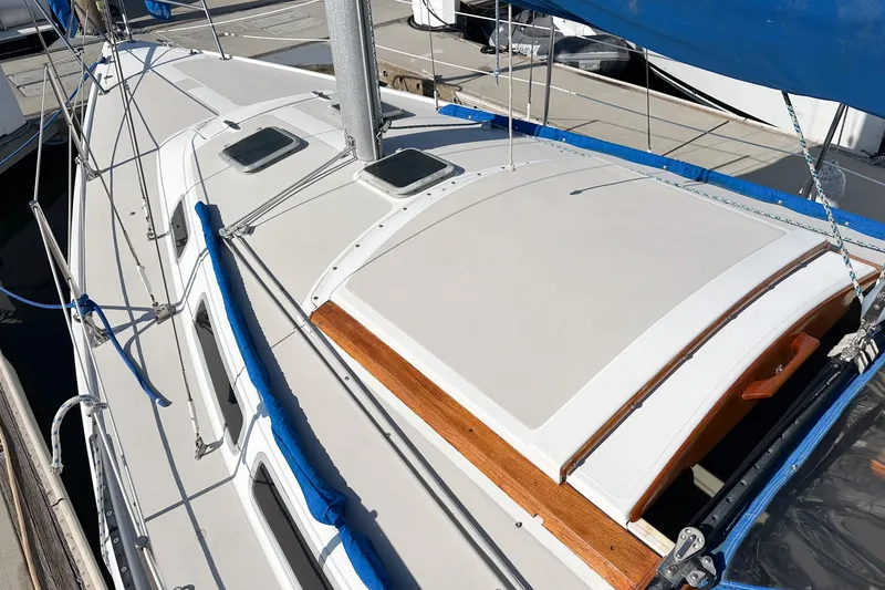 Slide: The Image of 1984 Catalina 30 sailboat deck with blue accents and wooden trim in marina. - 21