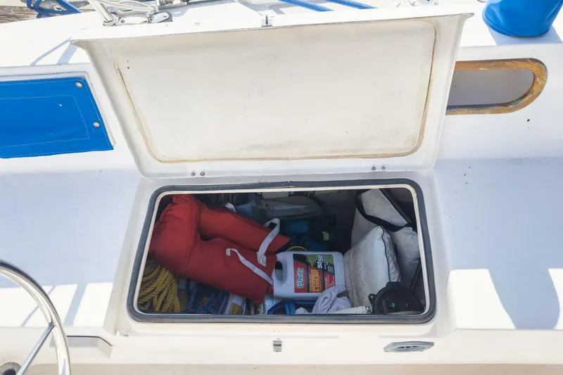 Slide: The Image of Open storage compartment on 1984 Catalina 30 sailboat, containing life jacket and cleaning supplies. - 43