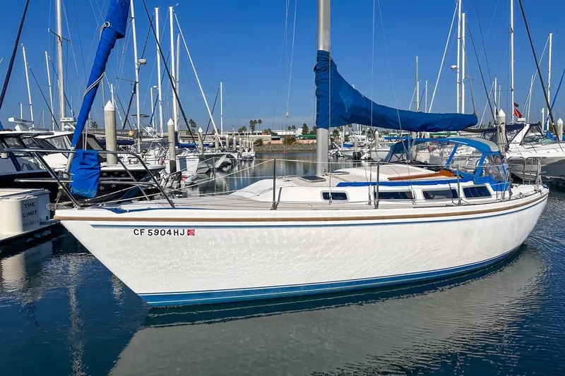 Slide: The Image of 1984 Catalina 30 sailboat docked in marina, featuring blue sail cover and calm water reflection. - 9