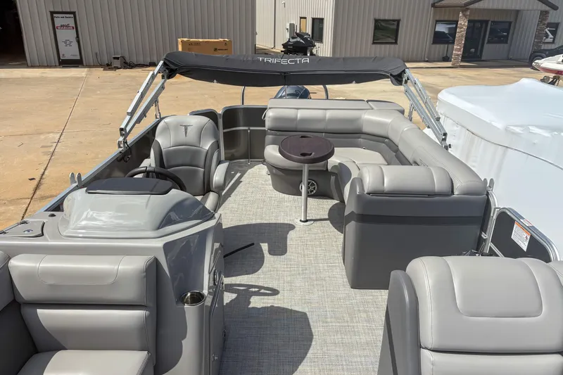Slide: The Image of 2021 Trifecta 22C CS 2.75 pontoon boat with gray seating and canopy, docked outdoors. - 12