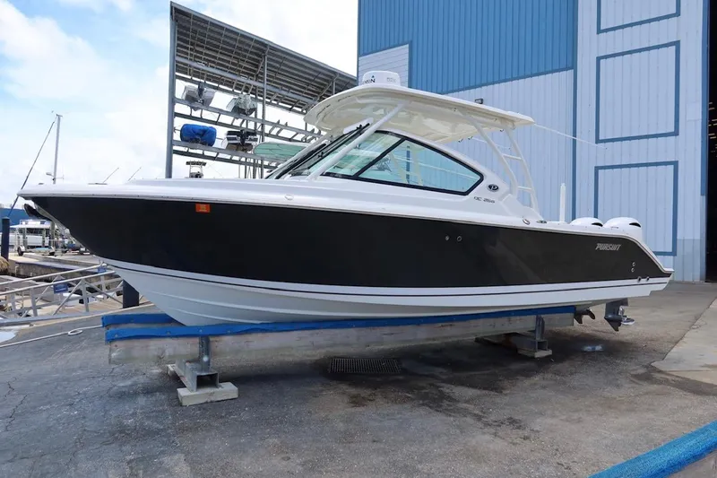 Slide: The Image of 2021 Pursuit DC 266 Dual Console boat on a dock, blue and white exterior. - 30