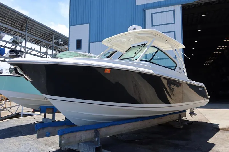 Slide: The Image of 2021 Pursuit DC 266 Dual Console boat on display in a marina setting. - 31