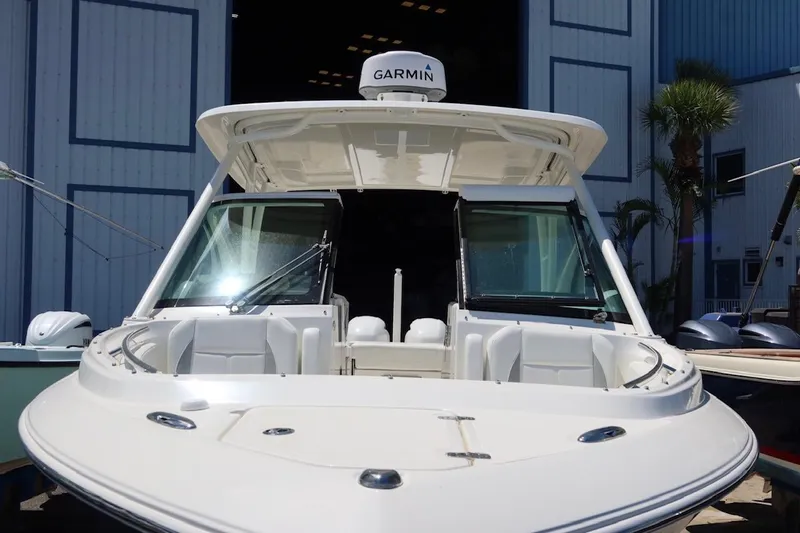 Slide: The Image of 2021 Pursuit DC 266 Dual Console boat with Garmin equipment, docked near a blue building. - 34