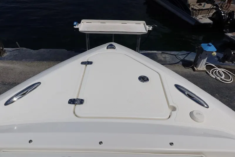 Slide: The Image of 2021 Pursuit DC 266 Dual Console boat bow at dock, featuring storage hatch and cleats. - 35