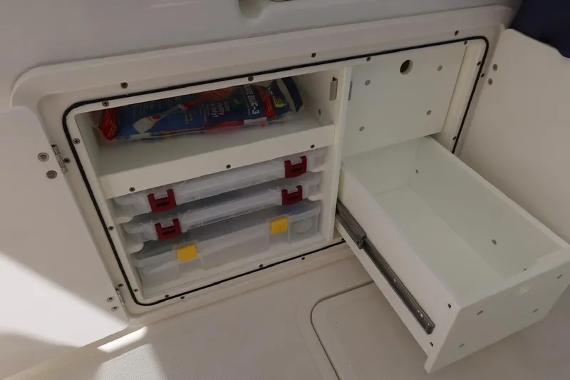 Slide: The Image of Storage compartment on 2021 Pursuit DC 266 Dual Console boat with organized tackle boxes. - 47