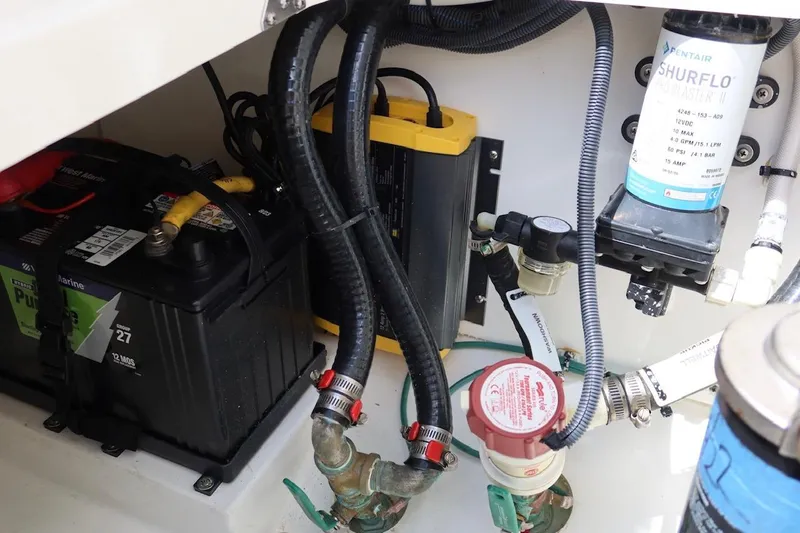 Slide: The Image of 2021 Pursuit DC 266 Dual Console boat engine compartment with battery and pump system. - 58