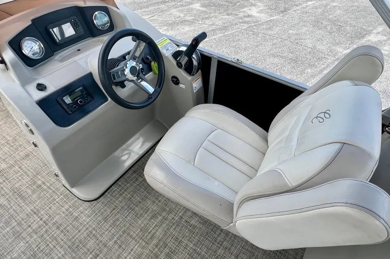 Slide: The Image of 2023 Cypress Cay Seabreeze 232 boat interior with steering wheel and captain's chair. - 15