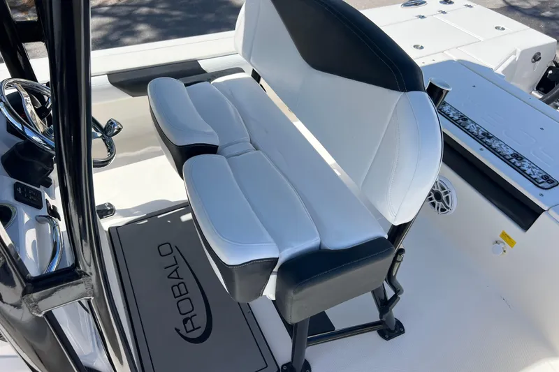 Slide: The Image of 2021 Robalo 246 Cayman SD boat interior with cushioned seating and steering wheel. - 15