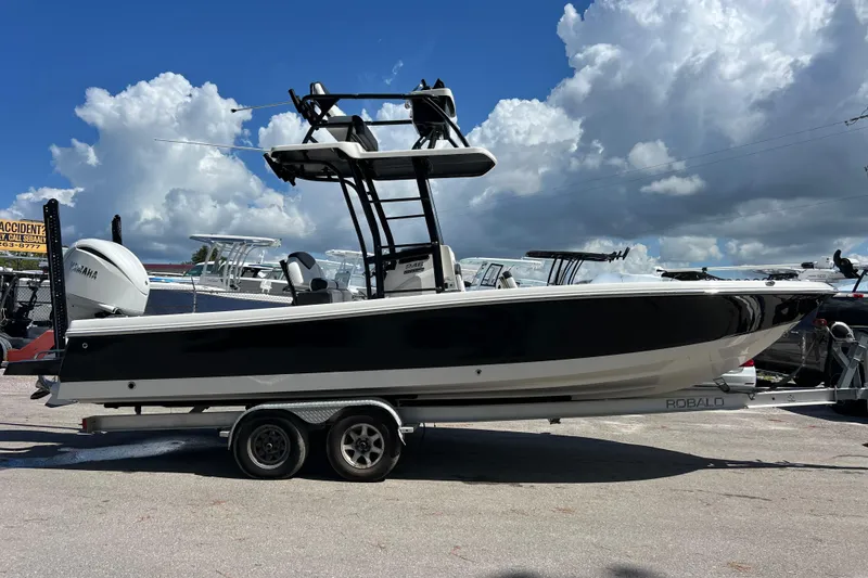 Slide: The Image of 2021 Robalo 246 Cayman SD boat on trailer under cloudy sky. - 2