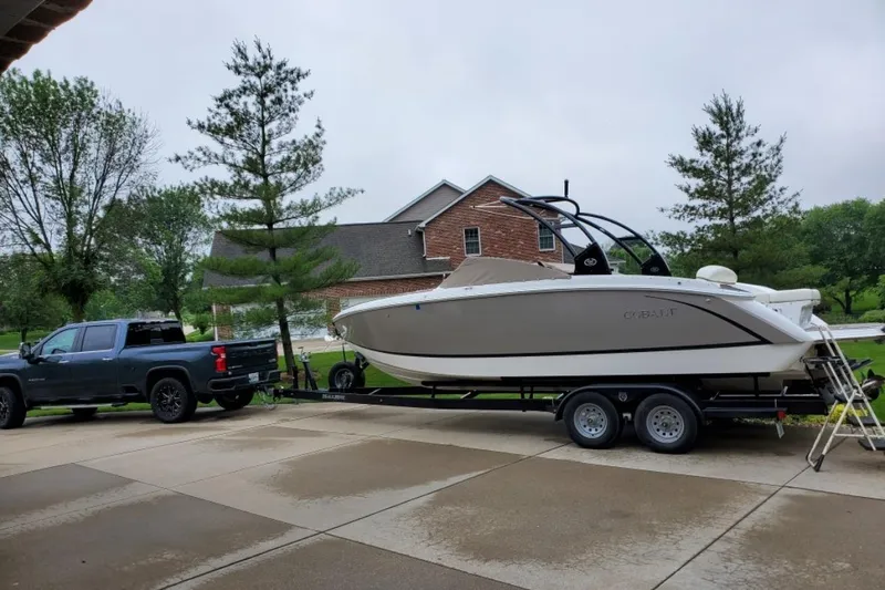 Slide: The Image of 2015 Cobalt R7 boat on trailer, parked in driveway beside a pickup truck. - 0