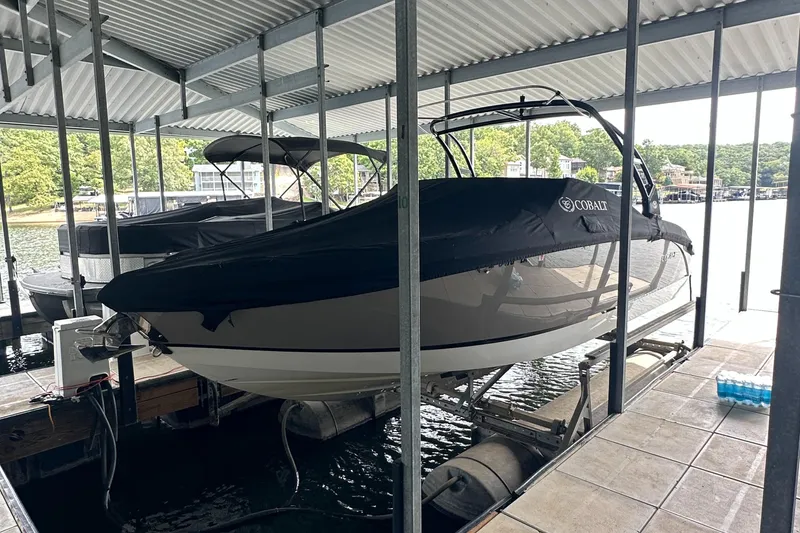 Slide: The Image of 2015 Cobalt R7 boat covered and docked in a marina, surrounded by water and trees. - 5
