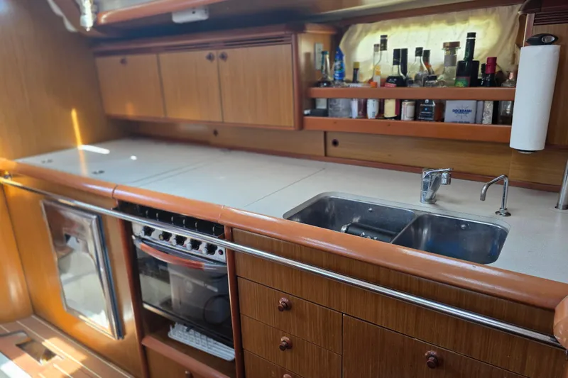 Slide: The Image of 2007 Jeanneau 49 Performance yacht kitchen with wooden cabinets, dual sink, and stove. - 31