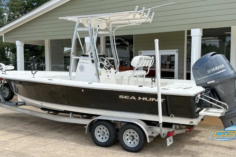 Slide: The Image of 2014 Sea Hunt BX 22 Pro boat on trailer with Yamaha outboard motor, parked outside a building. - 2